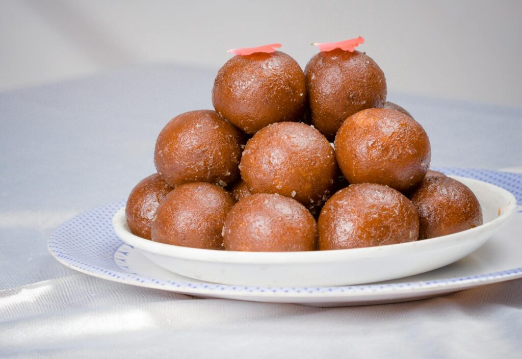 Close-up of a traditional Indian dessert, Gulab Jamun, served on a white plate.