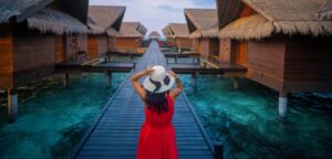 A woman in a red dress explores overwater bungalows in the Maldives, showcasing a tropical vacation setting.